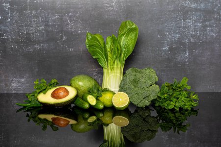 Foto de Fotografía de fondo de verduras verdes, brócoli, lima, menta, pepinos, aguacate, chile, pak choi, mango sobre un fondo gris. - Imagen libre de derechos
