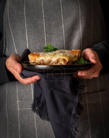 Photo for Food photography of lasagna, cheese, parmesan, oregano, hands, hold - Royalty Free Image