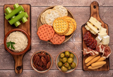 Foto de Fotografía de alimentos de aperitivo, hummus, apio, galleta, queso, brie cheddar, salami, prosciutto, aceitunas - Imagen libre de derechos
