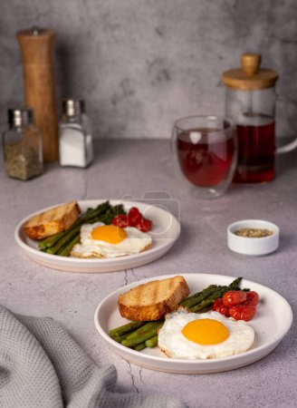 Foto de Fotografía de alimentos de huevo frito, tomate, espárragos, tostadas, té, sal, desayuno - Imagen libre de derechos