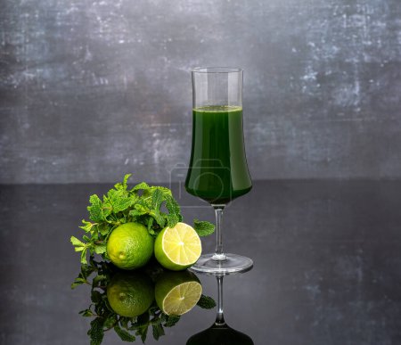 Téléchargez les photos : Photographie de fond de jus de légumes verts, légumes frais, citron vert, menthe, verre sur fond sombre. - en image libre de droit