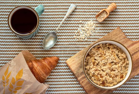 Photo for Food photography of breakfast, oatmeal porridge, croissant, mug of tea, spoon - Royalty Free Image