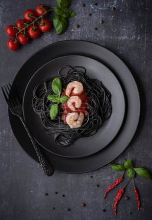 Téléchargez les photos : Food photography of black spaghetti with shrimp, tomato sauce, tomatoes, basil - en image libre de droit