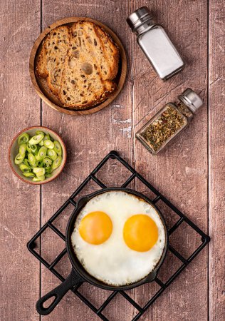 Photo for Food photography of breakfast, fried eggs, bread, toast, seasoning, salt, spring onion, frying pan, wooden, continental, background, homemade meal - Royalty Free Image