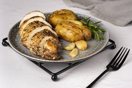 Photo for Food photography of roasted chicken, potato, garlic, rosemary, fork, knife, towel, meal, food - Royalty Free Image