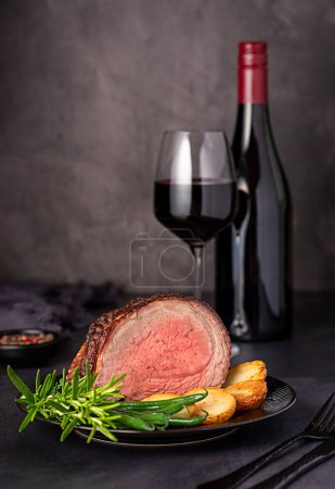 Photo for Food photography of roasted beef brisket, fillet; fried, potatoes, bean, rosemary, pepper, seasoning, red; wine; bottle; wineglass - Royalty Free Image