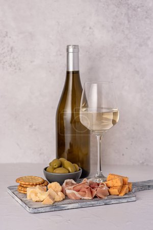 Photo for Food photography of antipasto, white wine, cheese, ham, serrano, olive, prosciutto, cracker, parmesan, cheddar, delicatessen - Royalty Free Image