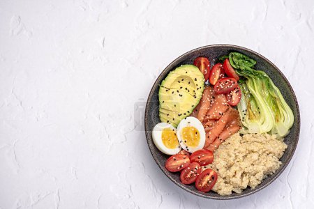 Foto de Fotografía de alimentos en blanco de desayuno saludable; brunch; buddha bowl; huevo; salmón; bok choy; tomate; quinua; aguacate; semillas de sésamo; proteína; carbohidratos; dieta - Imagen libre de derechos