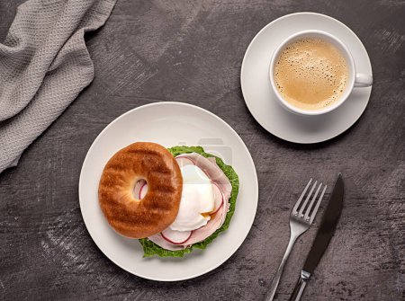 Photo for Food photography of bagel with poached egg, radish, bacon, ham, coffee, cappuccino, latte; Romaine lettuce; sandwich; morning; sliced; breakfast; brunch - Royalty Free Image