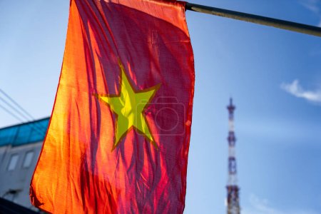 Vietnamese flag waving in the wind on a pole against a blue sky background