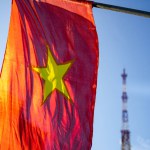 Vietnamese flag waving in the wind on a pole against a blue sky background