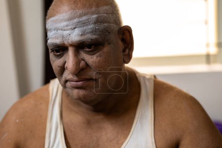 Photo for A sad fat man sits on a bed, looking down. - Royalty Free Image