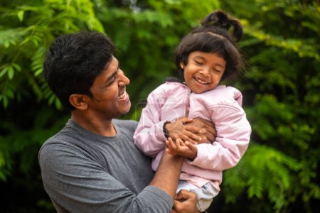 Photo for A loving Indian father and his daughter are smiling and enjoying a day in the park. - Royalty Free Image