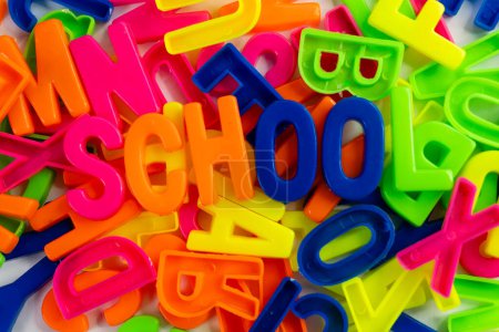 Téléchargez les photos : Cette image montre un ensemble d'aimants colorés disposés pour épeler les mots "École" sur un fond blanc uni - en image libre de droit
