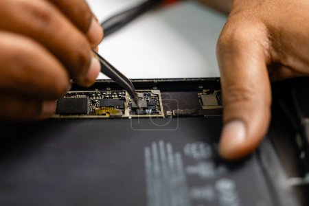 Téléchargez les photos : Une image d'un technicien concentré réparant méticuleusement une tablette - en image libre de droit