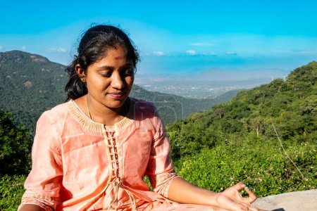 Photo for An Indian woman finds solace and oneness with nature in a meditative practice atop a majestic mountain peak - Royalty Free Image