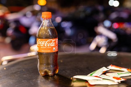 Téléchargez les photos : Une canette givrée de Coca-Cola, ornée de gouttelettes de condensation scintillantes, se trouve sur une table faiblement éclairée - en image libre de droit