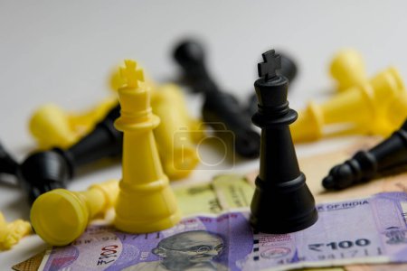 Photo for A strategic still life showcasing chess pieces locked in battle on a stark white backdrop, intermingled with stacks of coins and bills - Royalty Free Image