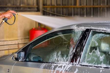A close-up view of a powerful car wash system, with thick foam cascading over a vehicle