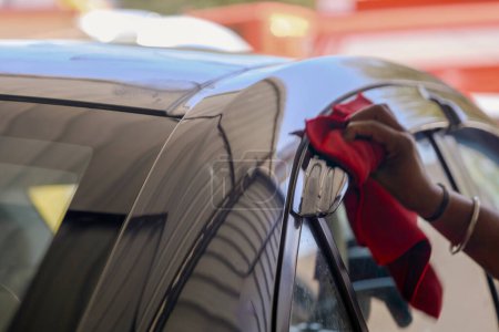 A dedicated auto detailer carefully buffs a car's exterior with a microfiber cloth