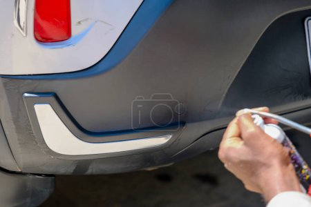 Ein Makrofoto, das die konzentrierte Sorgfalt und Detailarbeit beim Handpolieren eines Autos zeigt