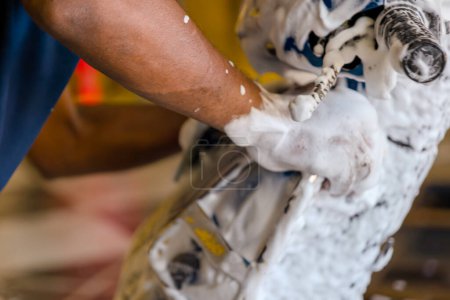 A close-up shot of a professional detailer meticulously polishing a motorcycle's body with a sponge