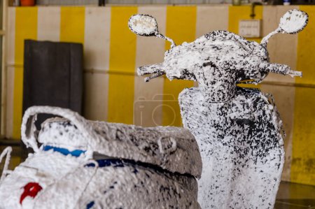 Photo for A close-up view of a scooter getting a thorough cleaning with thick foam and soap - Royalty Free Image