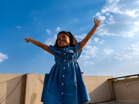 A radiant young girl throws her arms wide open