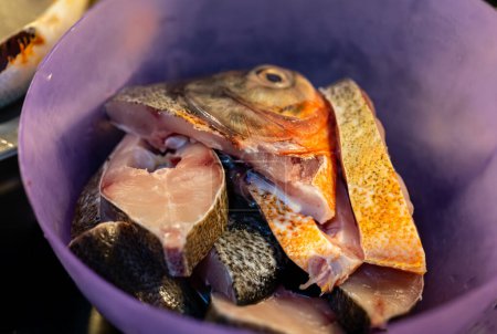 Eine fesselnde Nahaufnahme eines Marktstandes, der eine Reihe frischer Fische präsentiert, die kunstvoll in einer lebhaften lila Schüssel arrangiert sind
