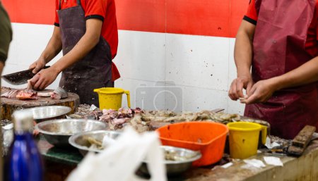 A close-up view of a vendor expertly cleaning prawns at a vibrant seafood market