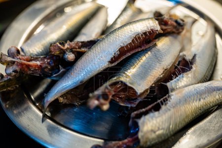 fresh sardines at a bustling fish market, their scales shimmering with an iridescent sheen