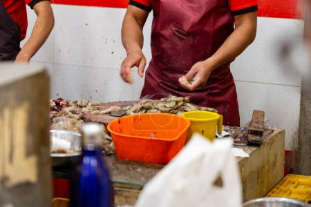 A close-up view of skilled hands cleaning fresh prawns at a vibrant seafood stall