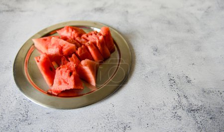A close-up photo of juicy watermelon slices arranged on a metal plate
