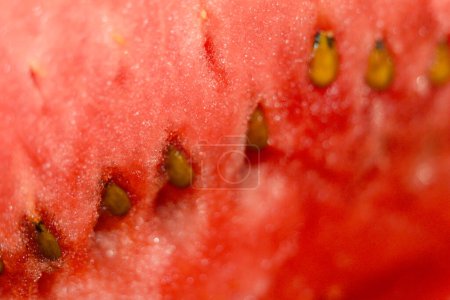Ein Nahaufnahme-Foto einer reifen, roten Wassermelonenscheibe, die ihre saftige Konsistenz und ihre Samen präsentiert.