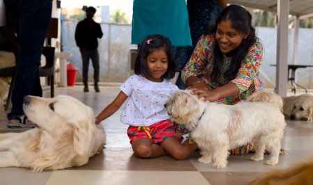 Eine entzückende Szene einer Mutter und ihrer Tochter, die bleibende Erinnerungen beim Spielen mit Hunden schaffen