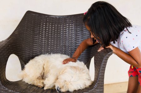 Una imagen conmovedora de una joven y su cachorro juguetón disfrutando de una tarde llena de diversión juntos, acurrucados en una acogedora silla de mimbre