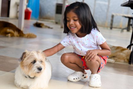 Une jeune fille asiatique rit avec délice alors qu'elle lutte ludique avec son chien