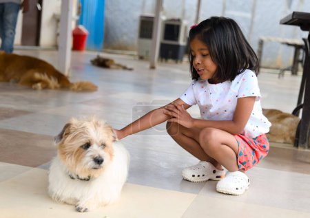 Une jeune fille asiatique rit avec délice alors qu'elle interagit avec son adorable chien