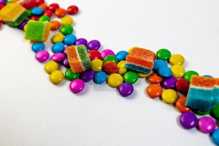 A burst of colorful candies in various shapes and sizes, scattered across a clean white background