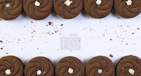 köstlicher Blick von oben auf frisch gebackene Schokoladenkekse, die über eine saubere weiße Oberfläche verstreut sind
