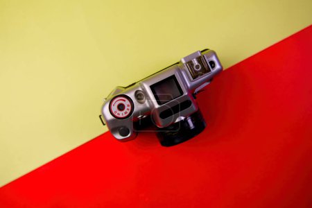 Une caméra vintage exposée sur un fond coloré dans une composition flat-lay