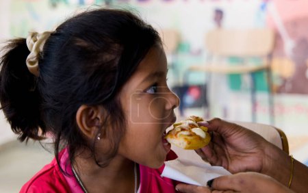 In diesem Bild geht es um ein junges Mädchen, das im Restaurant Pizza isst. Selektiver Fokus. und Mama füttert Pizza