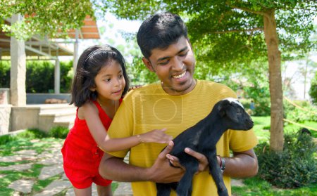 deliciosa imagen de un padre indio y su hija creando recuerdos felices mientras juegan con una encantadora cabra joven