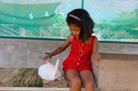 Foto de Una encantadora imagen de una joven pasando una tarde encantadora en su patio trasero, jugando con un conejo blanco esponjoso - Imagen libre de derechos
