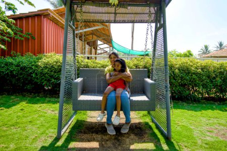 Photo for A delightful scene capturing a mother and her daughter enjoying a carefree moment on a swing in a vibrant garden - Royalty Free Image