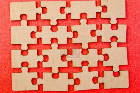 A close-up view of several wooden puzzle pieces fitting together seamlessly on a bright red background