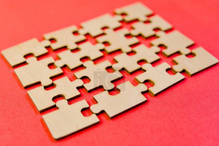 Téléchargez les photos : Vue rapprochée de pièces de puzzle en bois s'emboîtant parfaitement sur un fond rouge - en image libre de droit