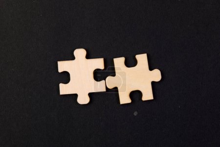 Foto de Esta imagen representa dos piezas de rompecabezas entrelazadas que se unen sin problemas sobre un fondo negro - Imagen libre de derechos