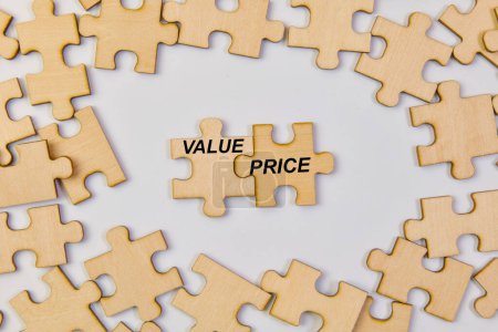 Holzpuzzleteile fügen sich zu den Wörtern "Wert" und "Preis" zusammen und symbolisieren, dass die Berücksichtigung beider Faktoren entscheidend für den Erfolg ist.