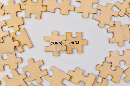 Téléchargez les photos : Image conceptuelle présentant des pièces de puzzle en bois entrelacées formant les mots "CONS" et "PROS." - en image libre de droit
